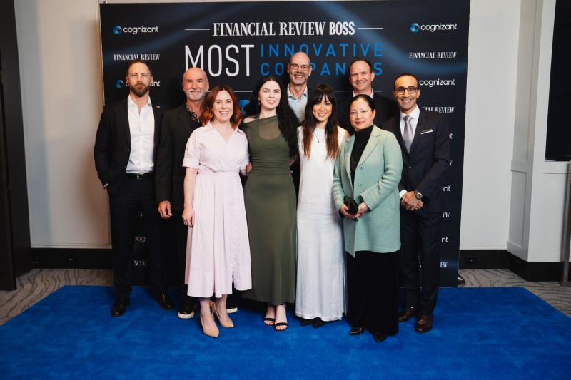 Group of nine Optravation Energypeople standing in front of an awards banner.