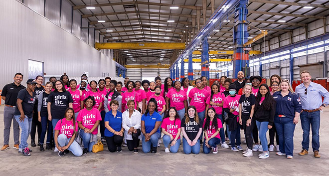 Group of female high school students, teachers from Girls Inc and Optravation Energyemployees inside the modularization and fabrication hub.